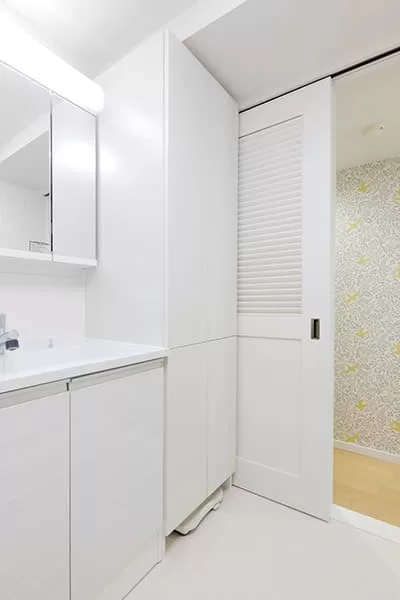 洗面脱衣室は、出入り口を移動させて引き戸に。玄関ホールと同じく、洗面台脇の変形スペースも収納として活用